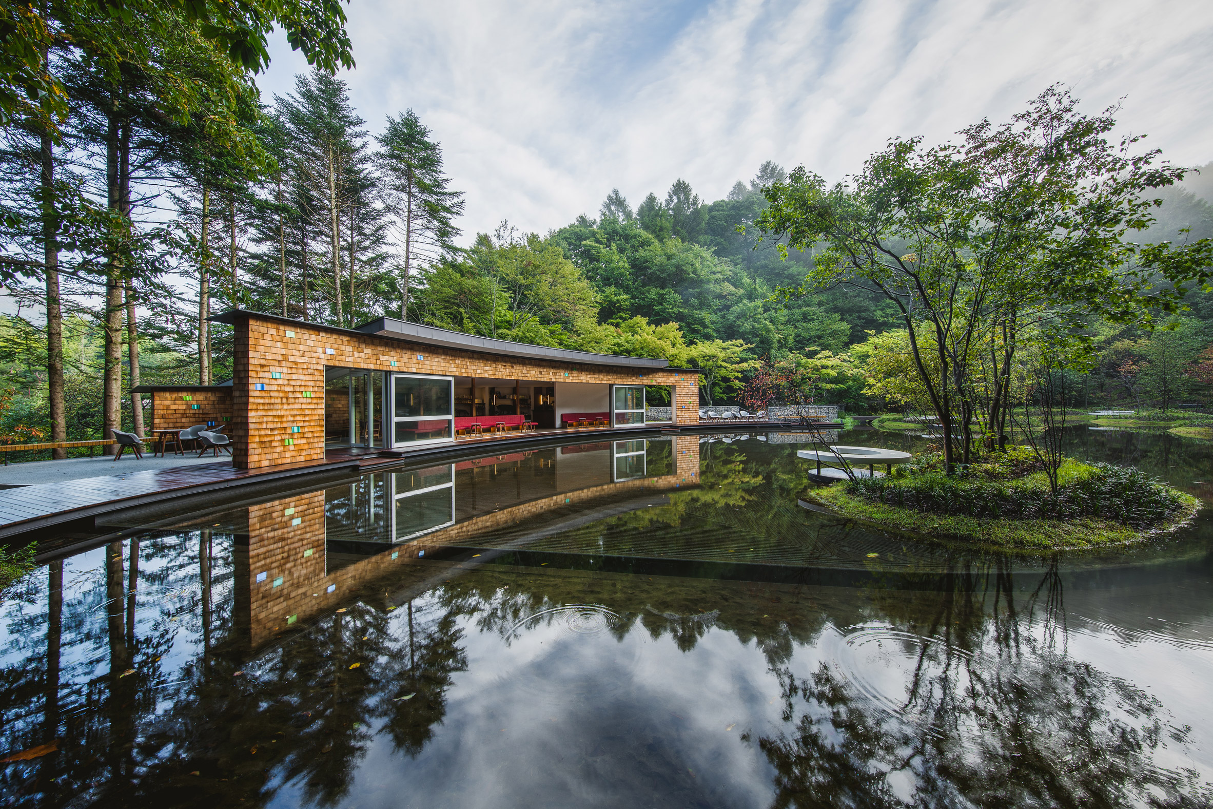 Shingled clubhouse and visitor centre faces ice rink in a Japanese forest-14