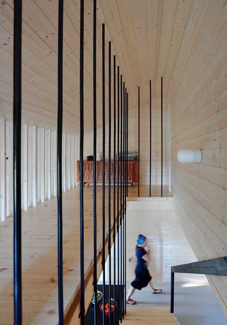 Black gabled house hewn from pine wood sits in the middle of a Polish forest-11