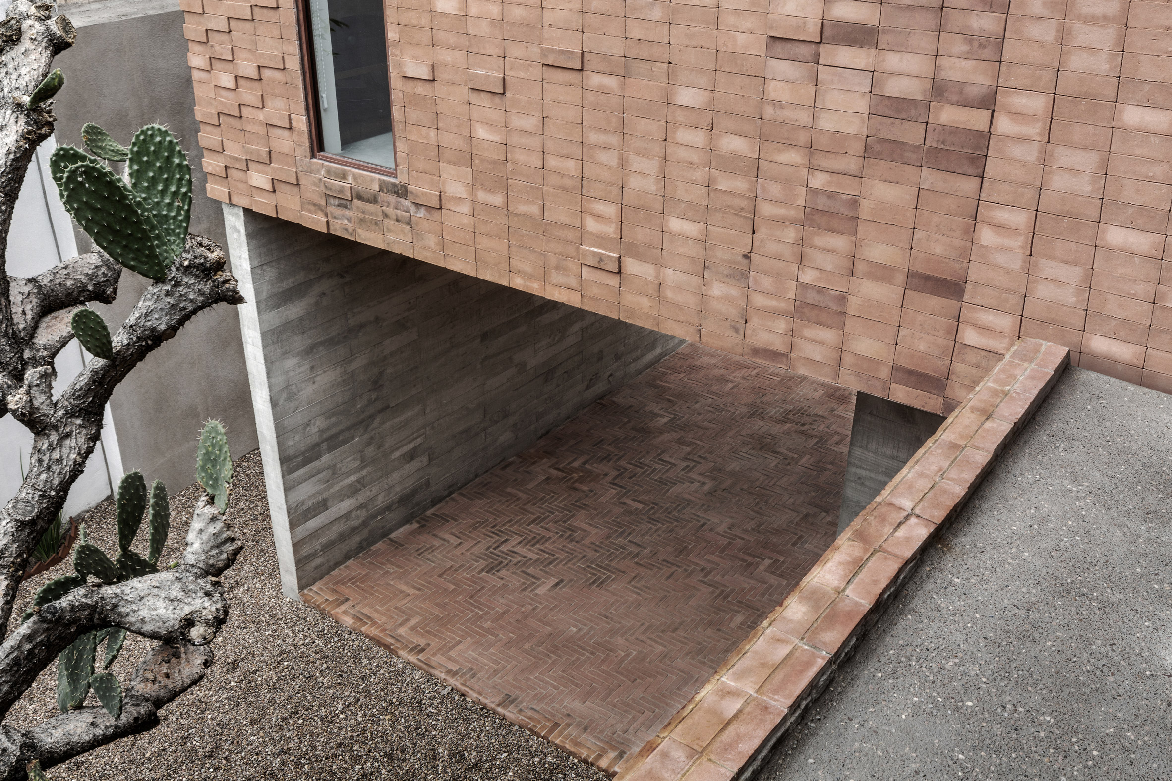 Clay brick and concrete Mexican house is set around a cactus tree-19
