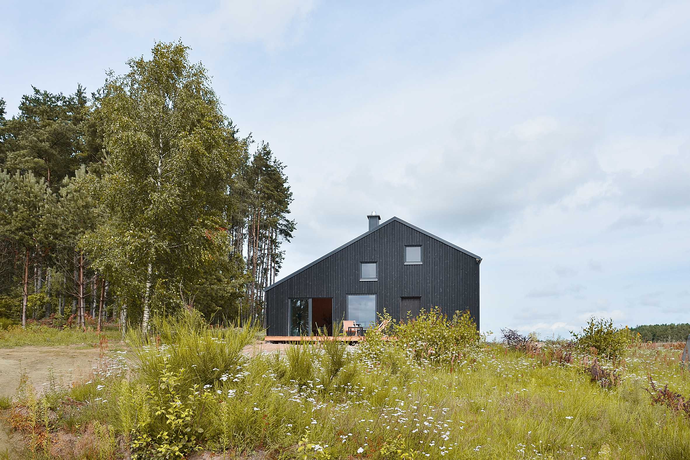 Black gabled house hewn from pine wood sits in the middle of a Polish forest-2