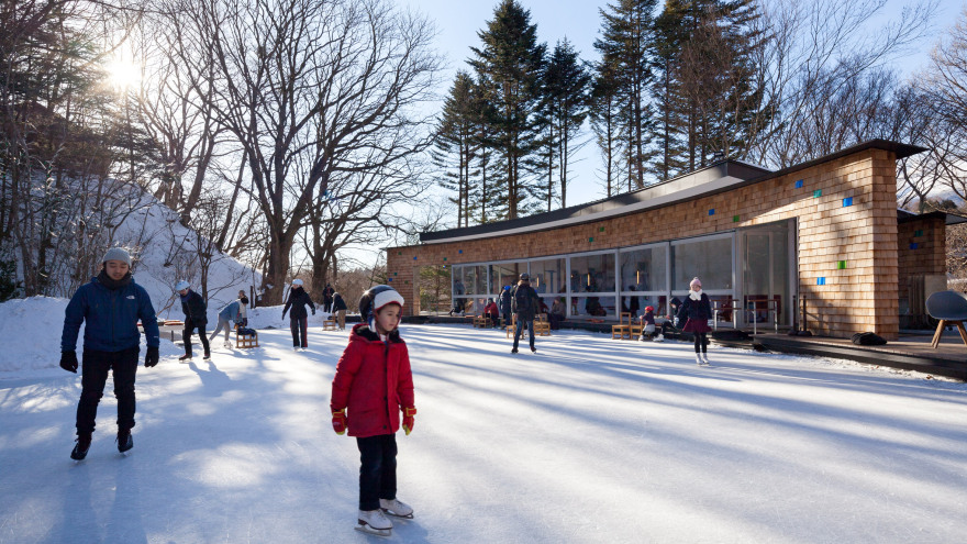 Shingled clubhouse and visitor centre faces ice rink in a Japanese forest-0