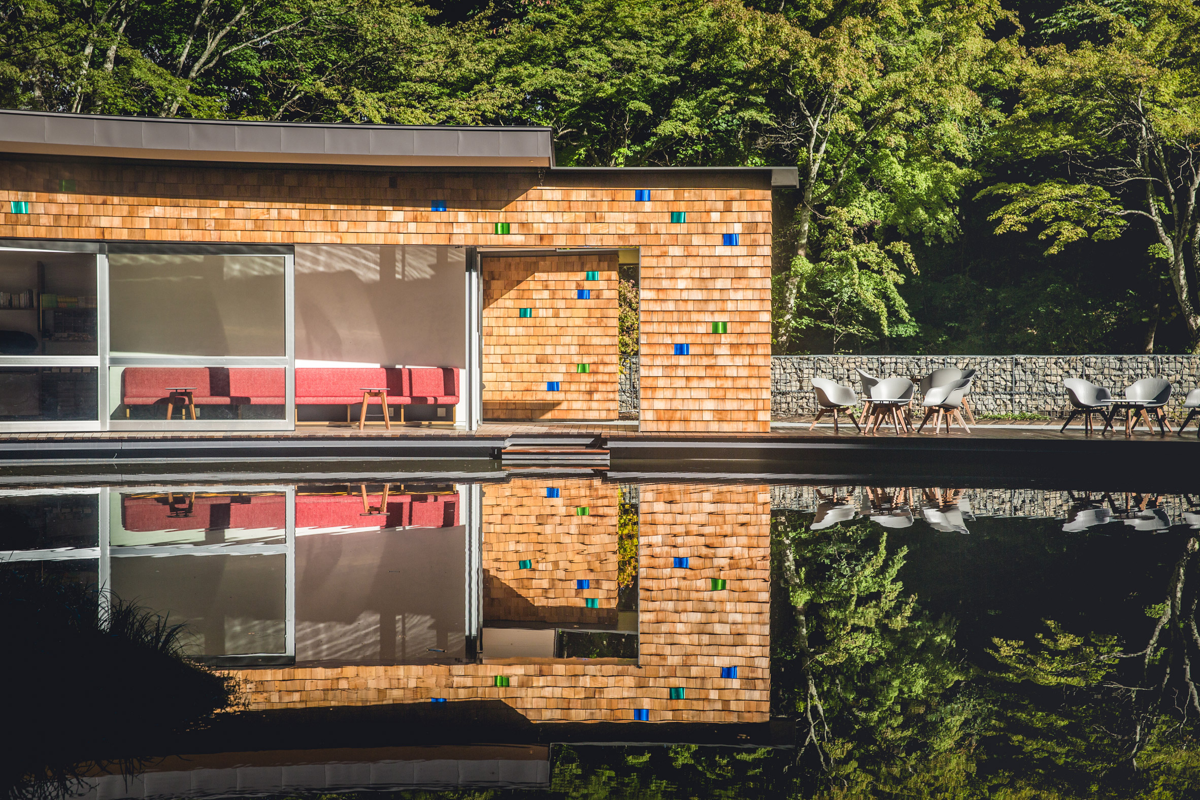 Shingled clubhouse and visitor centre faces ice rink in a Japanese forest-11