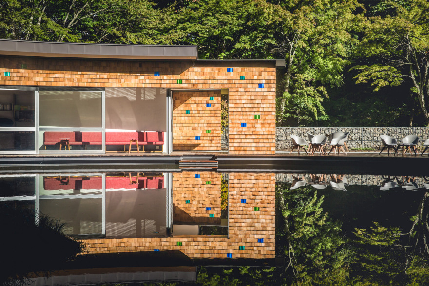 Shingled clubhouse and visitor centre faces ice rink in a Japanese forest-11