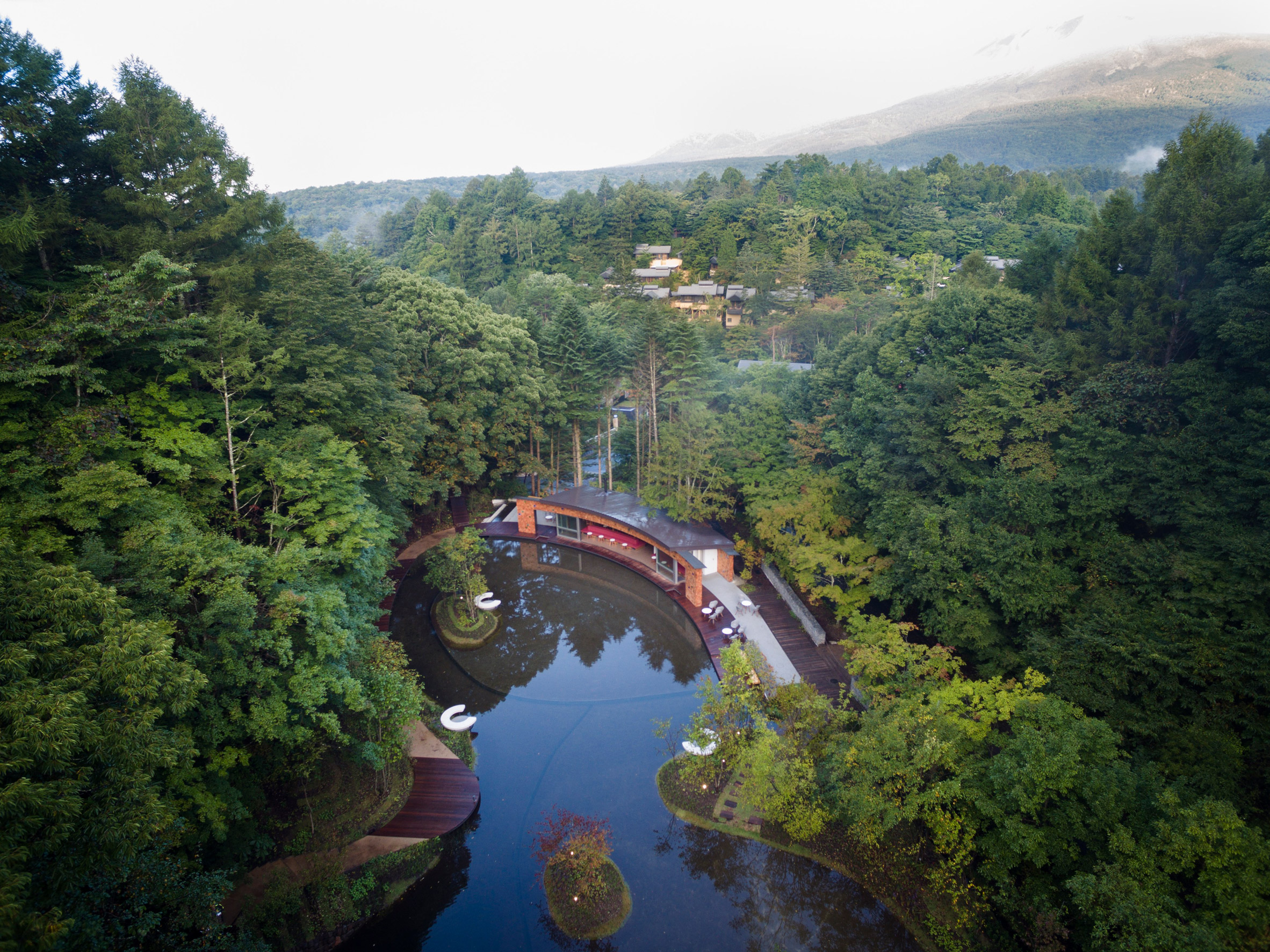 Shingled clubhouse and visitor centre faces ice rink in a Japanese forest-8