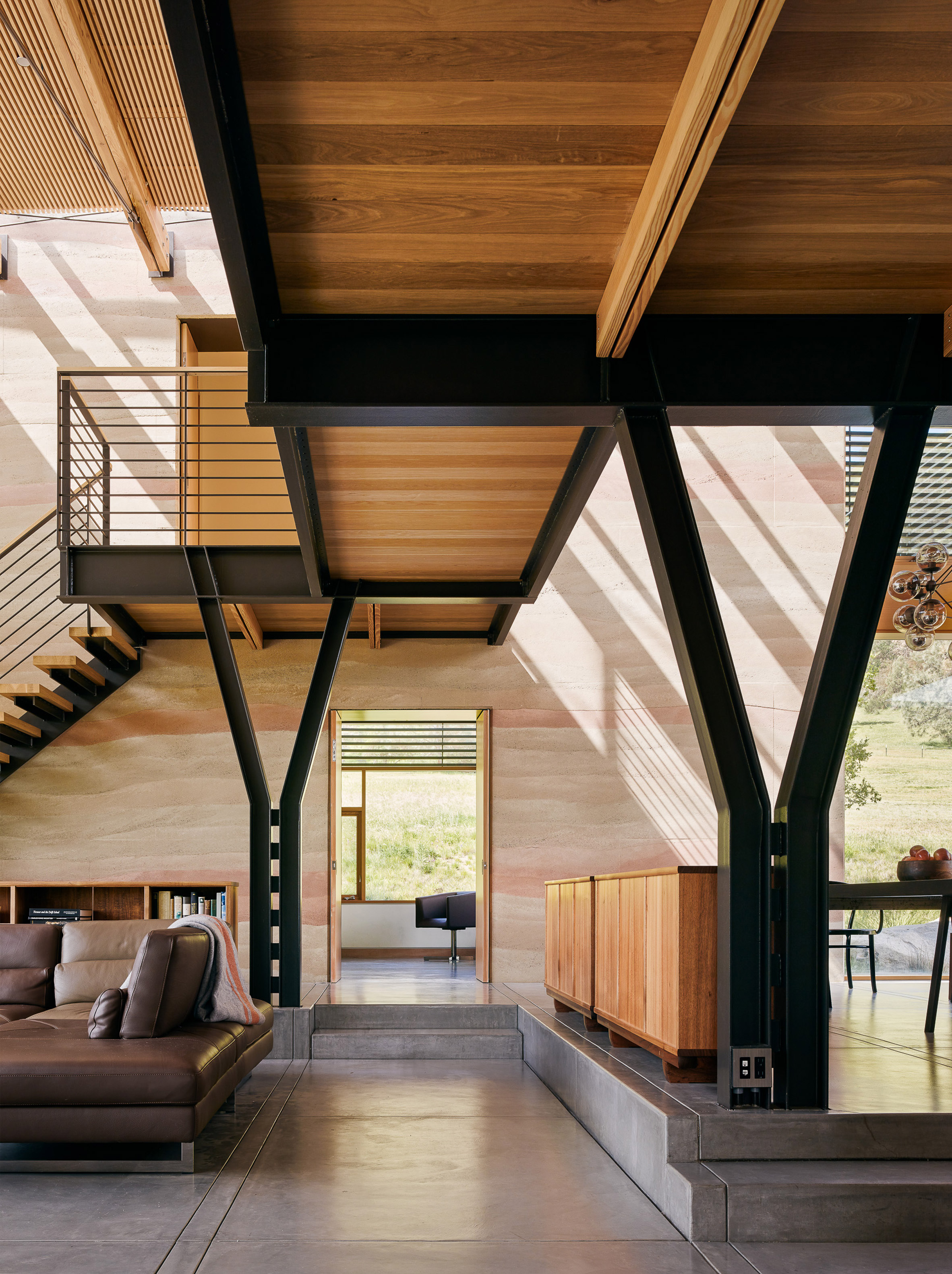 Stripey rammed-earth walls curve through holiday house in Californian walnut farm-14