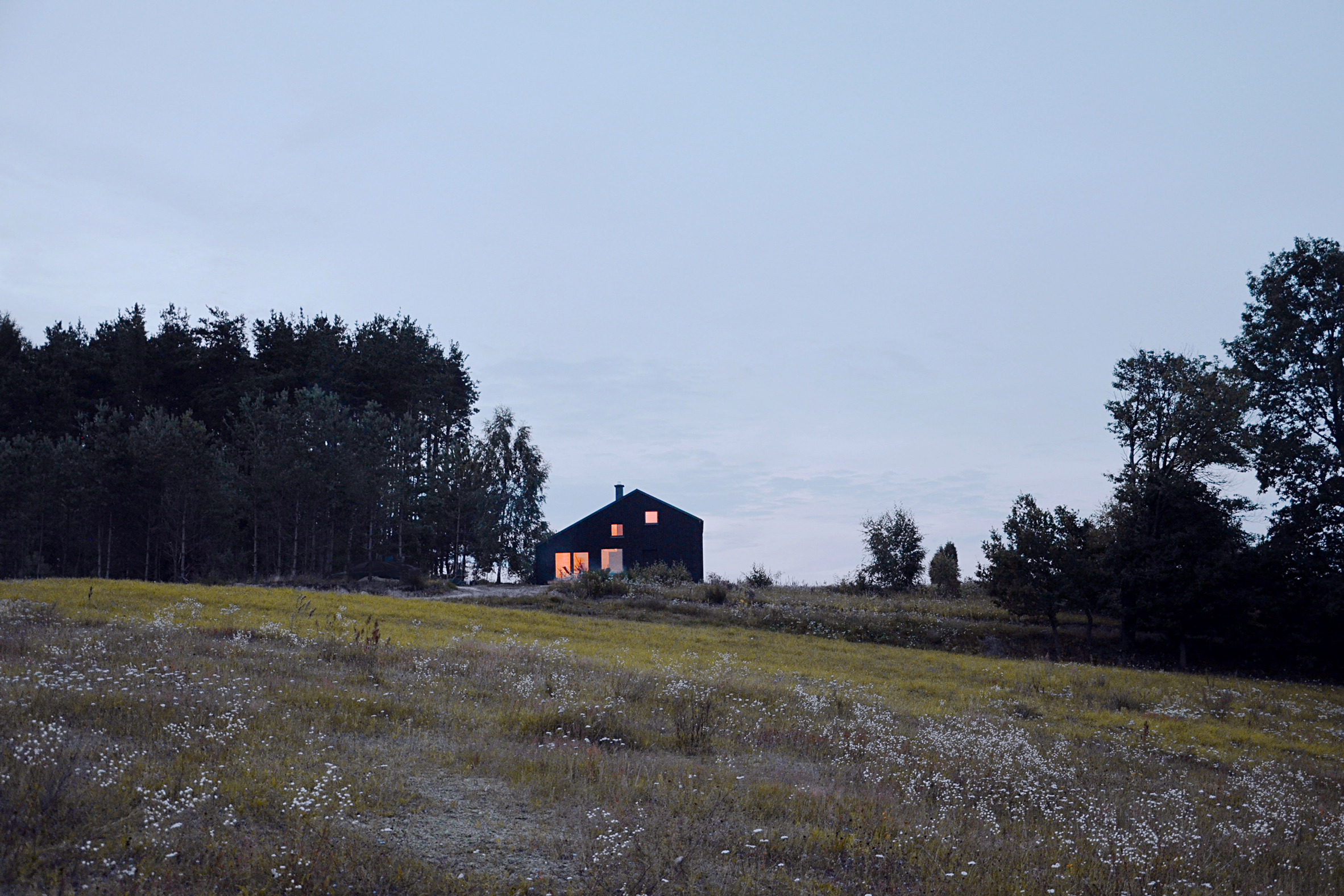Black gabled house hewn from pine wood sits in the middle of a Polish forest-18