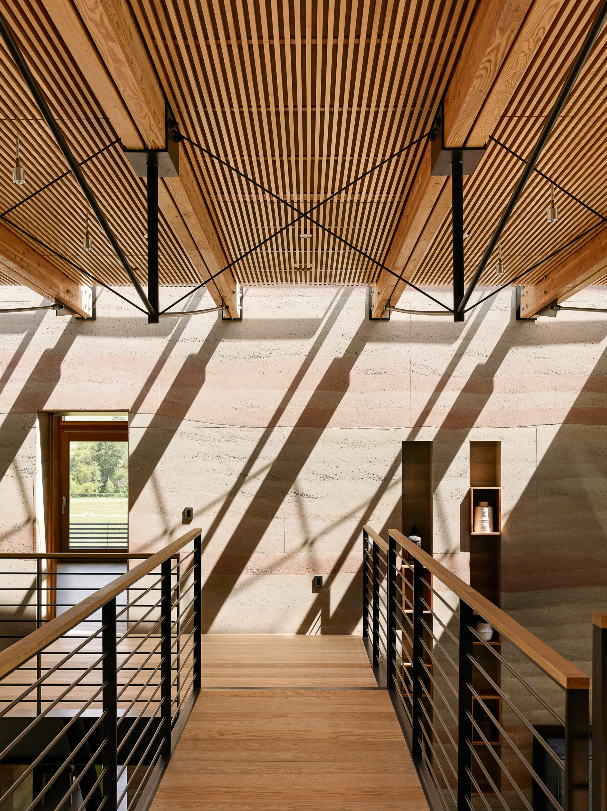 Stripey rammed-earth walls curve through holiday house in Californian walnut farm-20