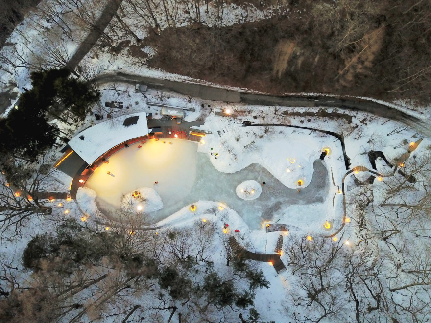 Shingled clubhouse and visitor centre faces ice rink in a Japanese forest-2