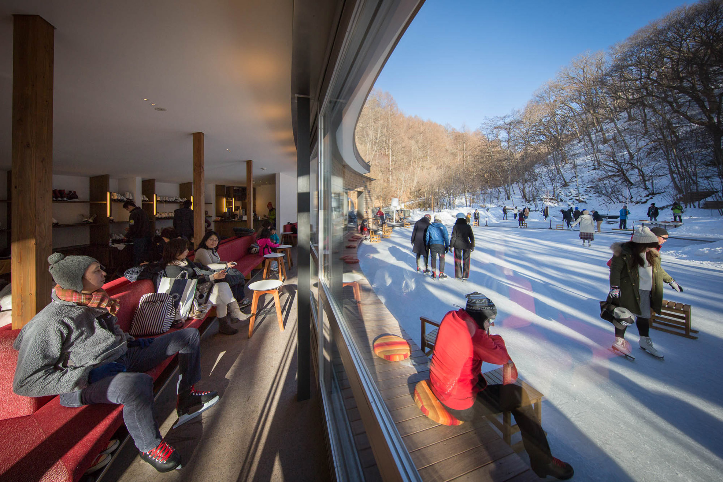 Shingled clubhouse and visitor centre faces ice rink in a Japanese forest-5